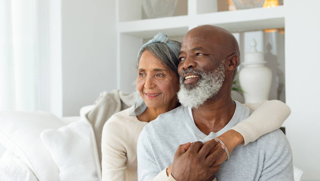 Front view of senior diverse couple sitting on a white couch in beach house