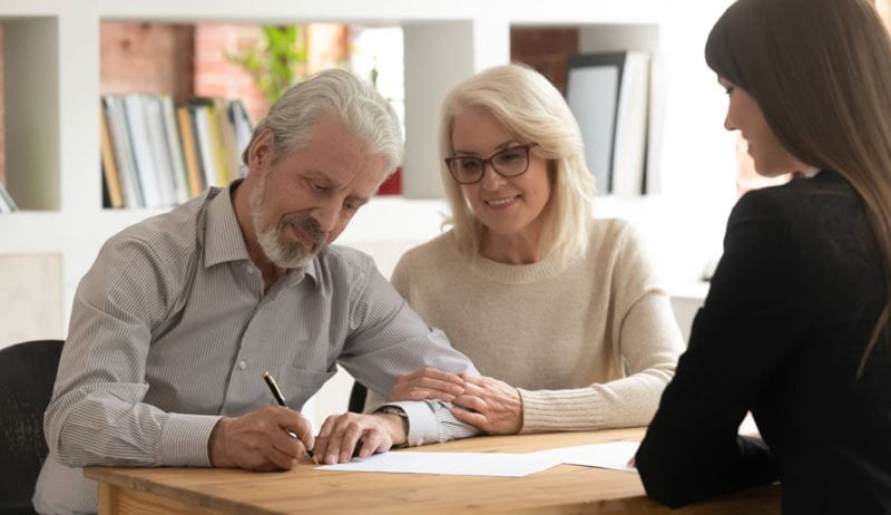 Happy mature husband and wife sign contract closing deal with female bank specialist taking loan together, pensioner clients couple meeting with realtor put signature on agreement buying property