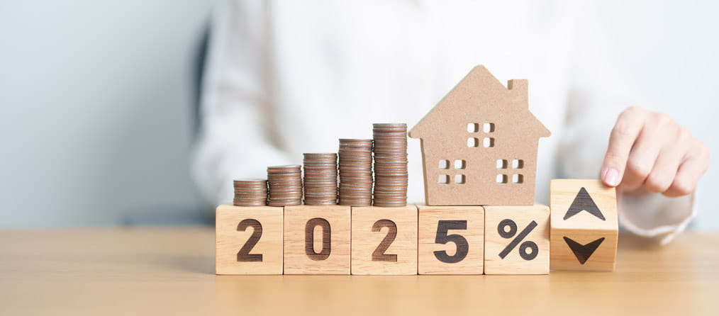 A home model and coin stack sitting on wooden blocks spelling 2025