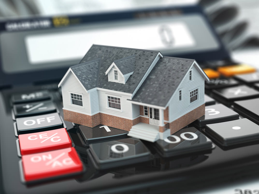 A model house sitting on a calculator