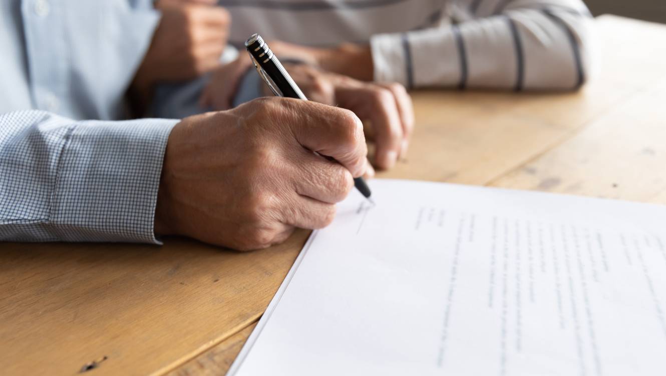 Close up elderly senior family couple signing contract with real estate agent purchasing accommodation, making agreement with financial advisor or putting signature on paper medical insurance.