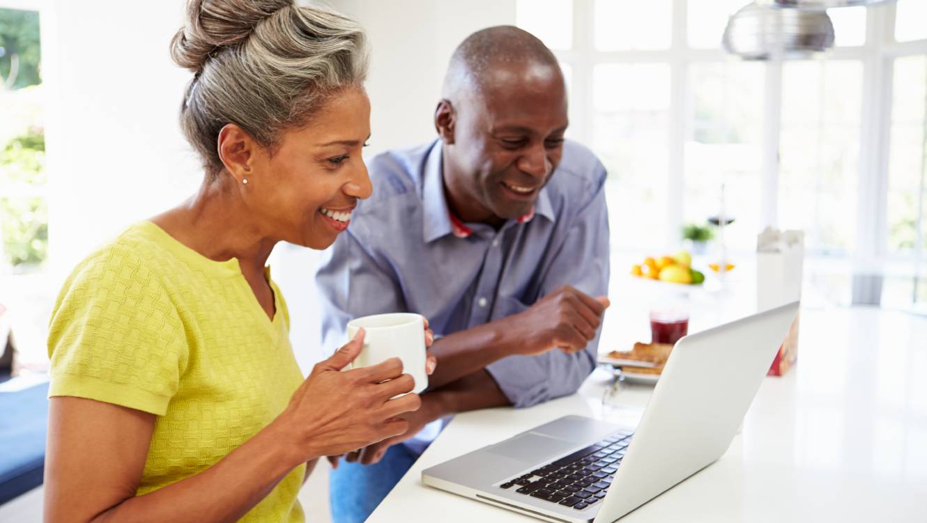 Mature African American Couple Using Laptop At Breakfast