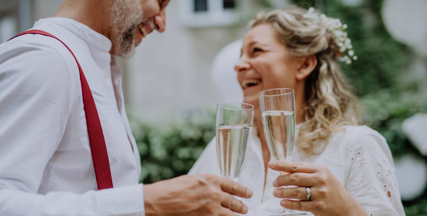 Mature bride and groom toasting at wedding reception outside in the backyard.