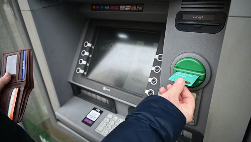 Person is taking out his bank card from the cash machine.