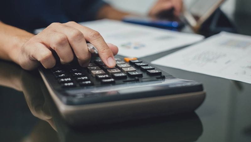 Businessman hand with calculator at the office and financial data analyzing business result and tax management. Finance accounting and economy concept.