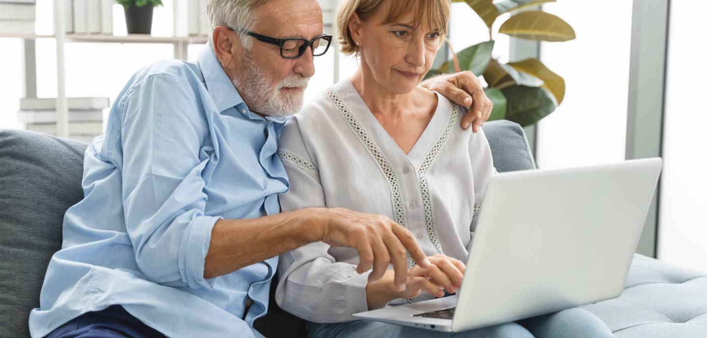 A mature couple using laptop computer together on a sofa