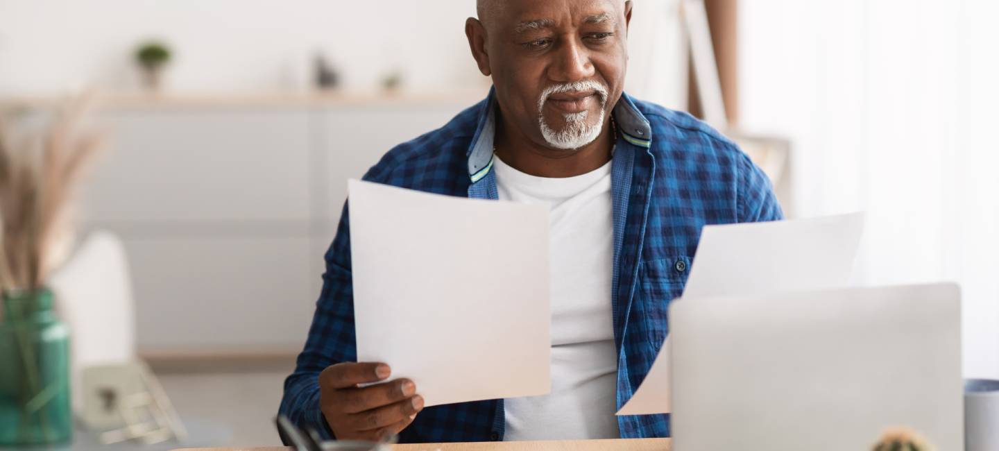 Mature man looking at  his paperwork while sitting at his desk