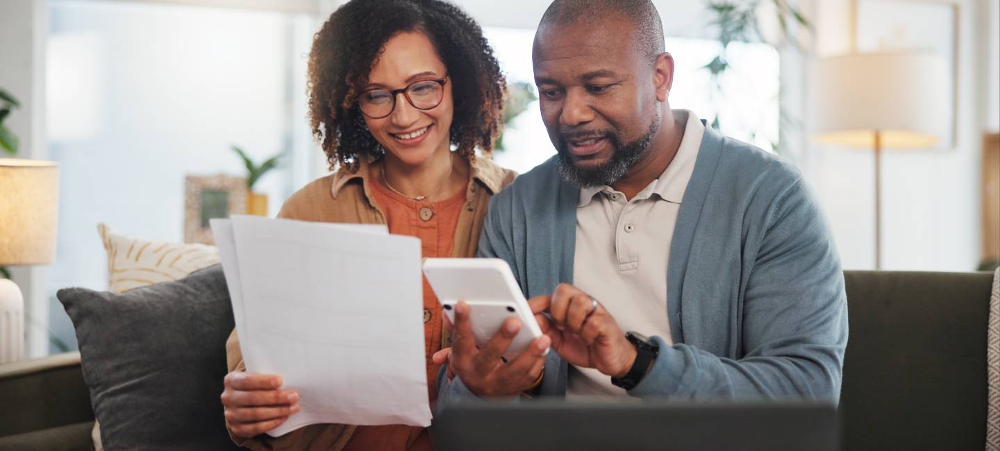 Mature couple sitting on the sofa calculating savings and expenses