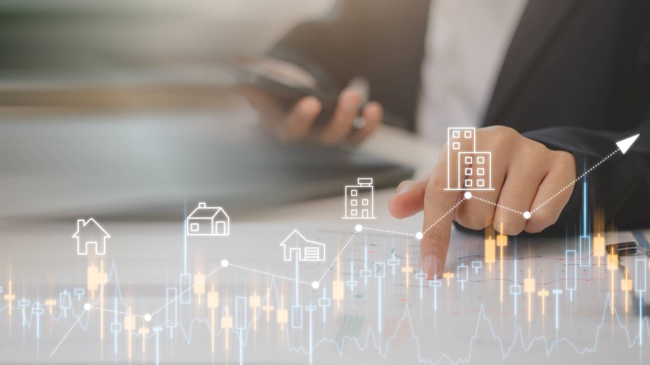 Businessmen analyze residential real estate investments using digital graphs and house icons, indicating market trends, investment, and property growth.