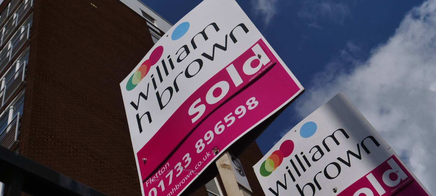 A row of estate agents' signs indicating properties For Sale, Sold and To Let outside an apartment block in Peterborough city centre.