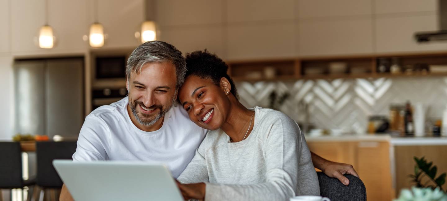 Mature couple smiling while looking at their laptop