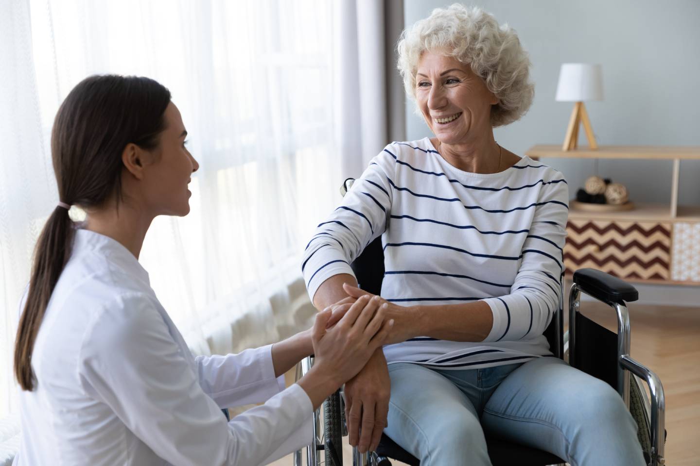 young doctor carer helps a mature woman in wheel chair