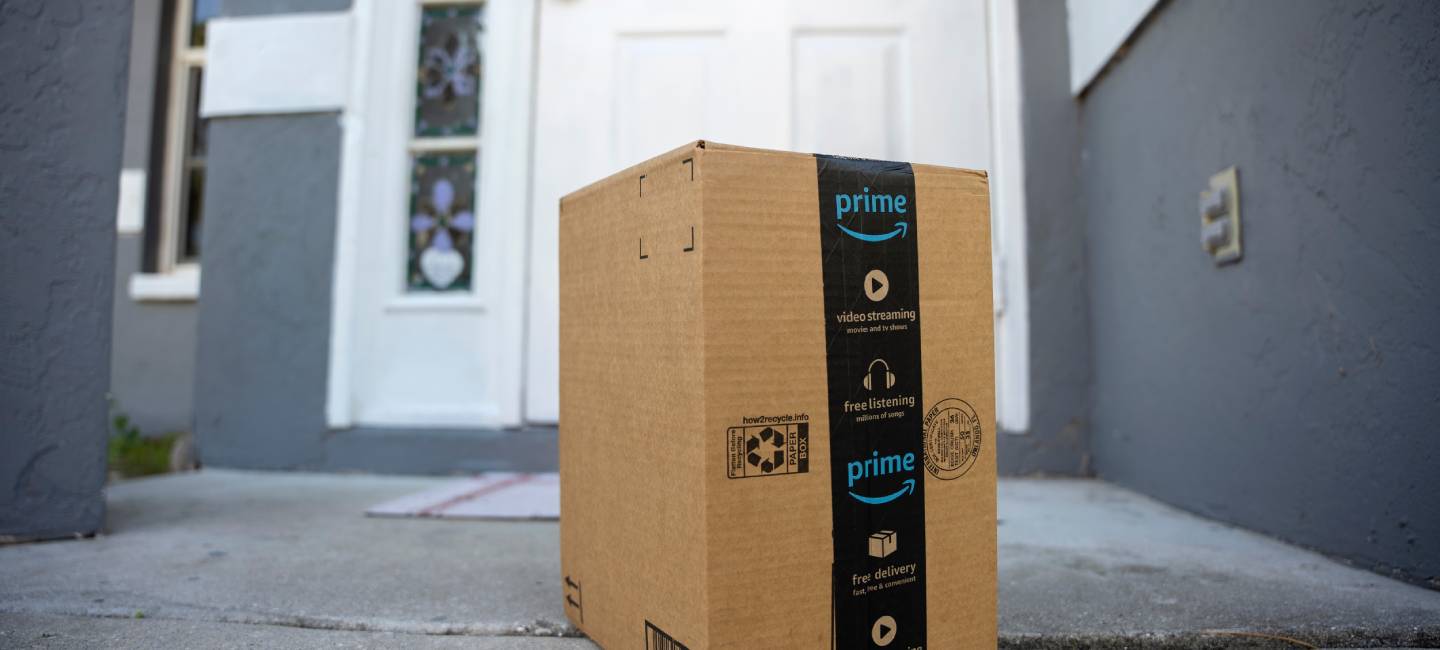 Amazon Prime package box with purchased online products delivered in front of house door. 