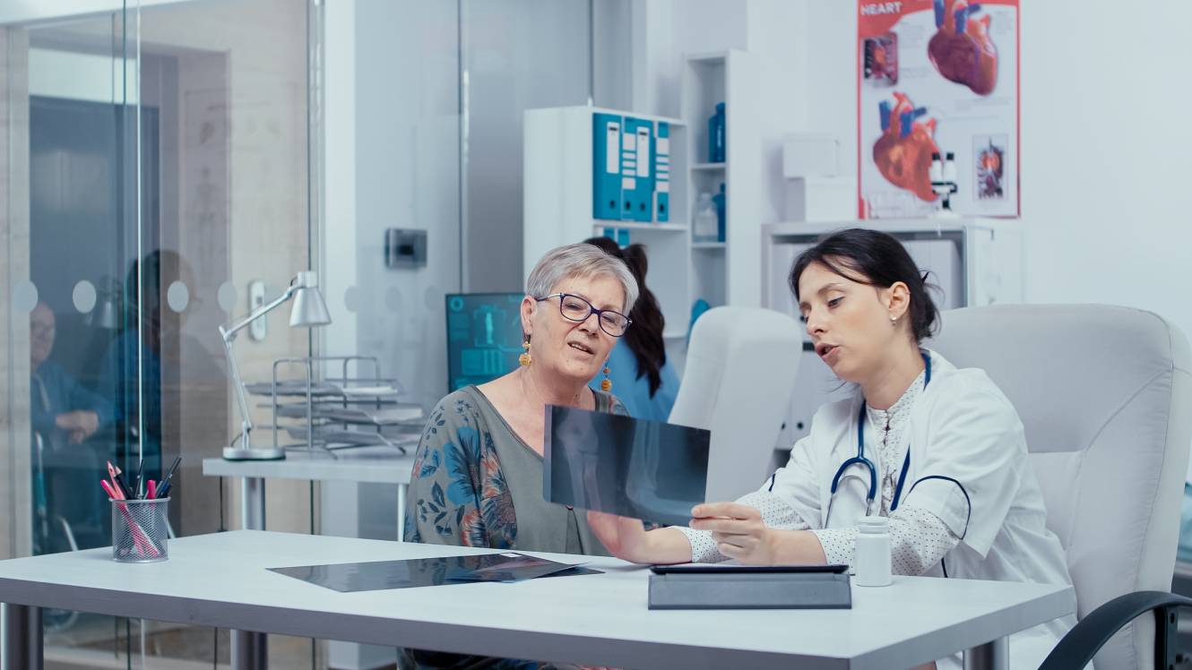 Doctor using x-rays to consult with patient in modern private healthcare hospital