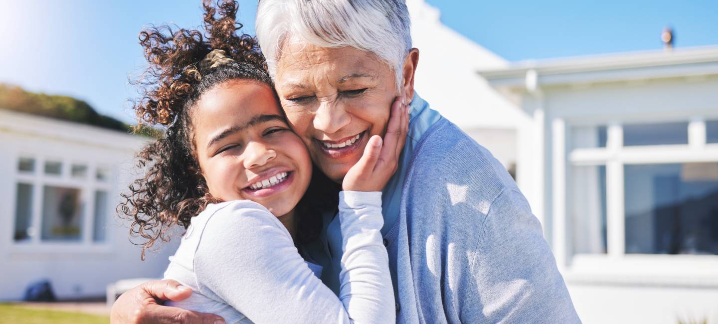 Grandmother hugging granddaughter outside on holiday