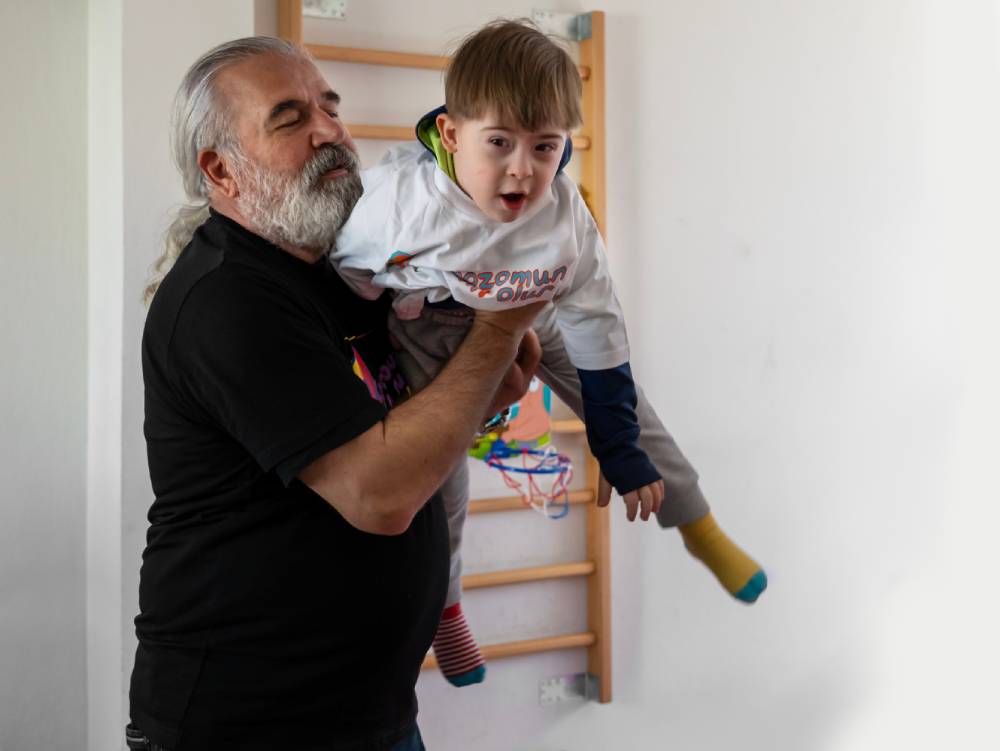 A little boy with autism and Down syndrome is smiling and playing various games with his teacher in the school classroom at the education center