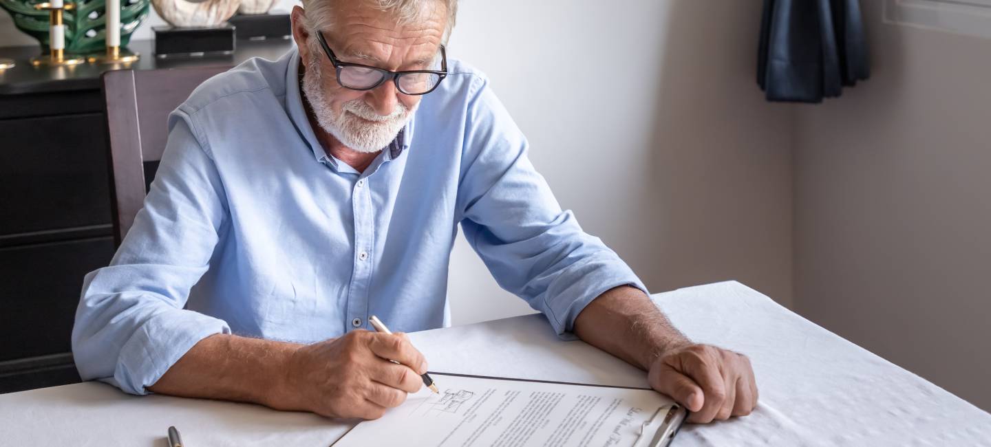 Senior old man elderly examining and signing last will and testament