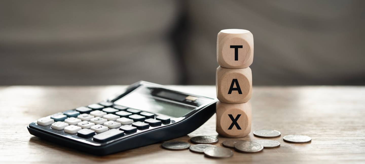 Tax Concept. Wooden Blocks with Calculator and Coins with the Word Tax