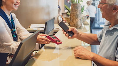 A senior man is paying for a hotel stay using a contactless payment method
