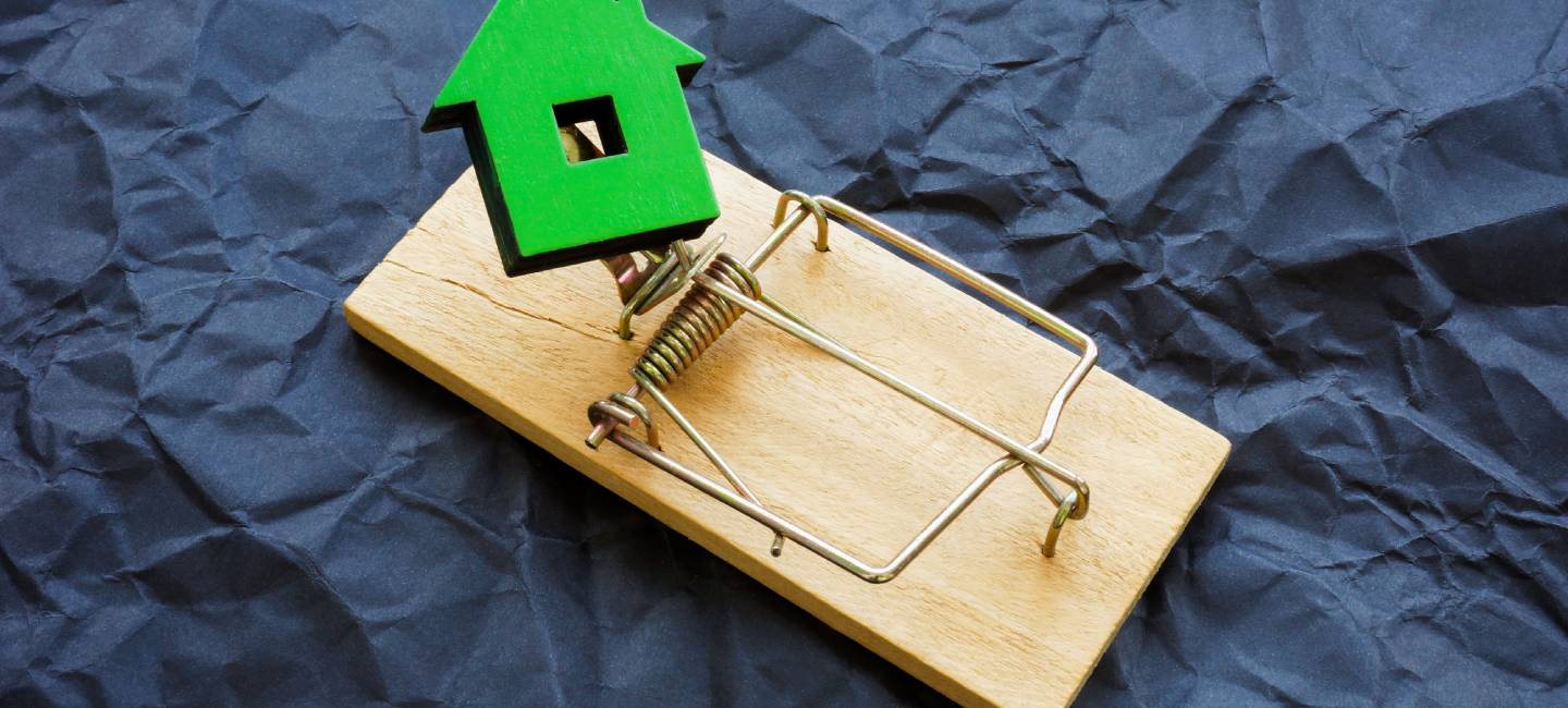 Small house trapped as a symbol of real estate fraud.