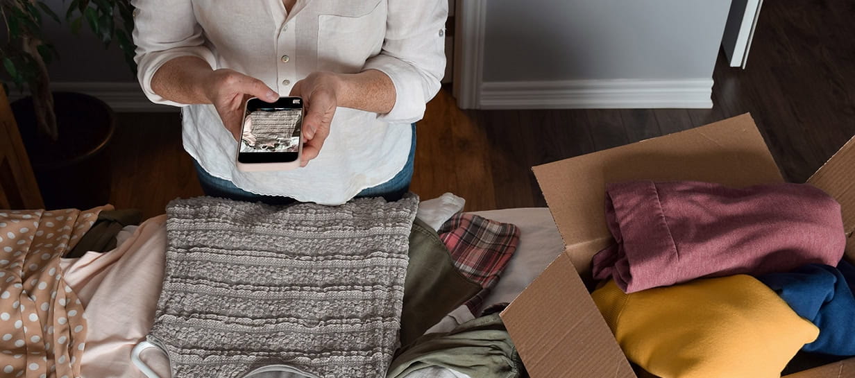Woman taking a picture of her unwanted clothing items to resale online.