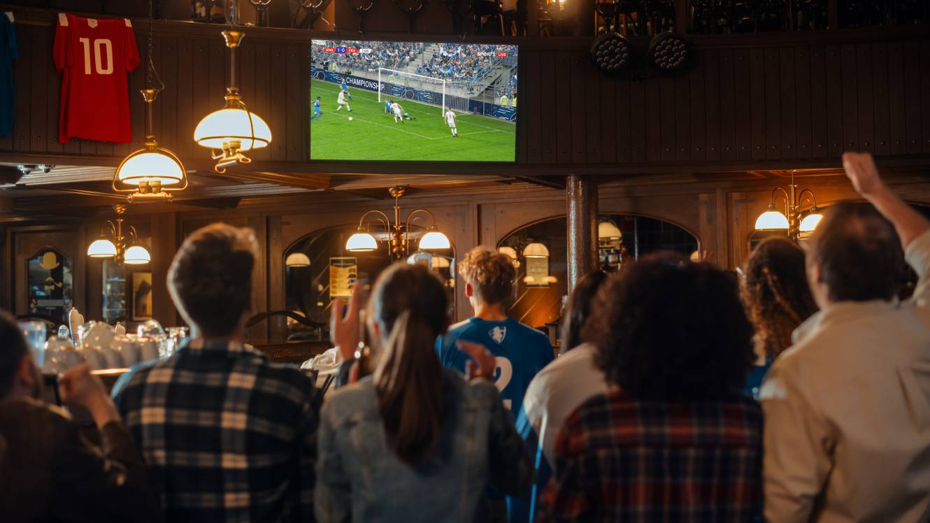 Group of Friends Watching a Live Soccer Match on TV in a Sports Bar.