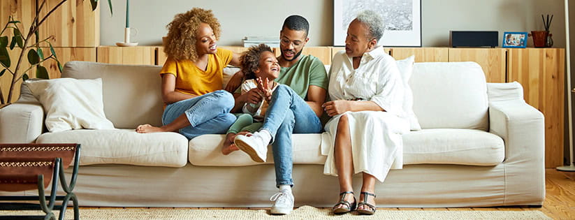 A multigenerational family sat together on a sofa at home