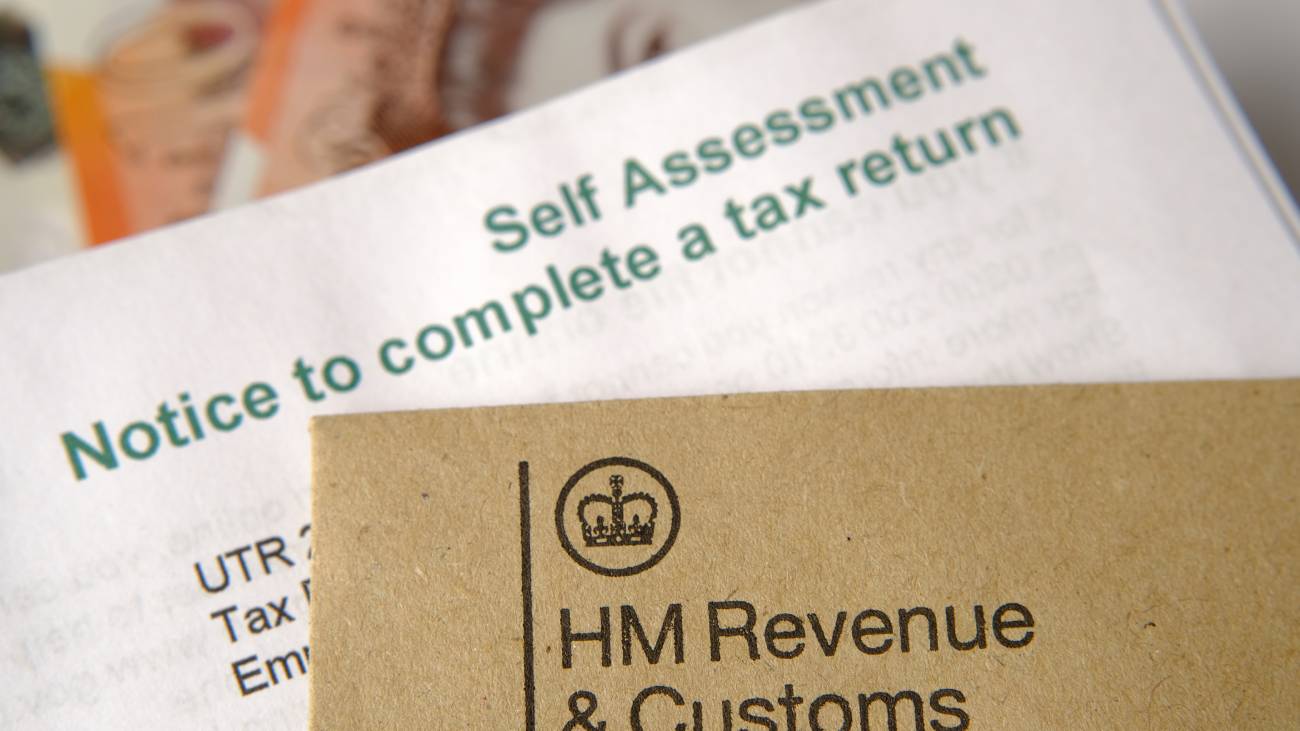 HM Revenue and Customs (HMRC) letters seen with logos with the brown envelope and blurred self assessment and tax return notice letter. Selective focus.