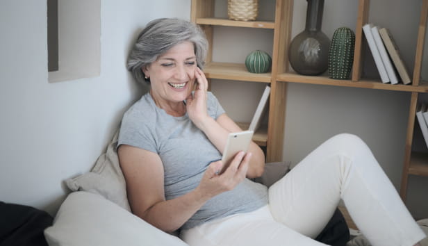 A woman sitting and smiling at her mobile phone