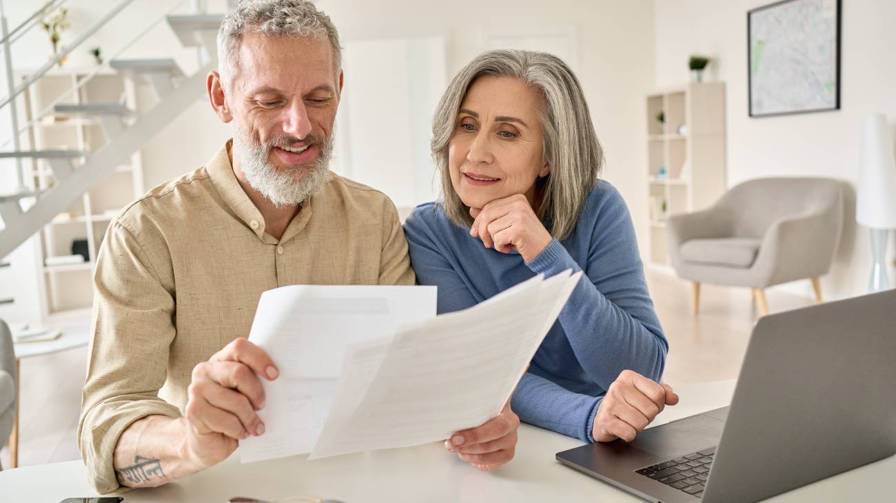 Mature male and female couple looking at their taxes while sitting at a table with a laptop
