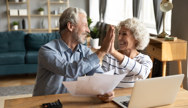 Man and woman sat behind a computer and high fiving each other 