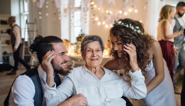 Bride and groom hugging grandmother at wedding 