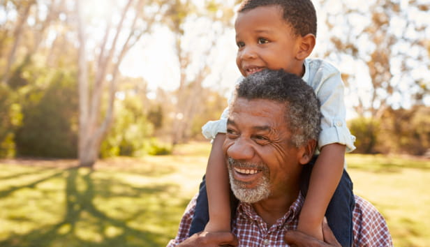 A little boy sitting on his Granddad's shoulders - both are very smiley