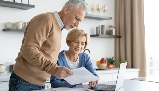 A man and woman looking at paperwork and a laptop 