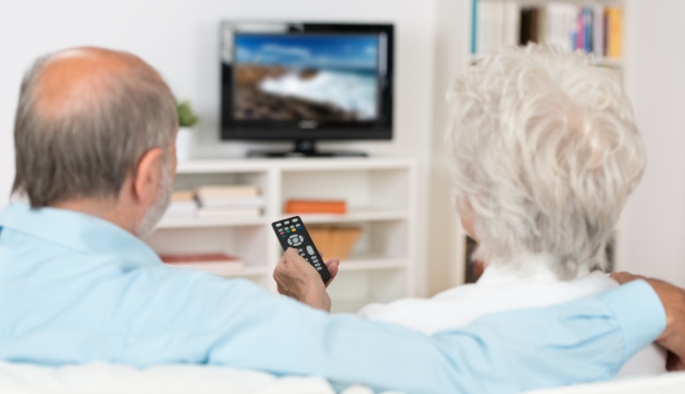 A couple sat on the sofa watching the TV