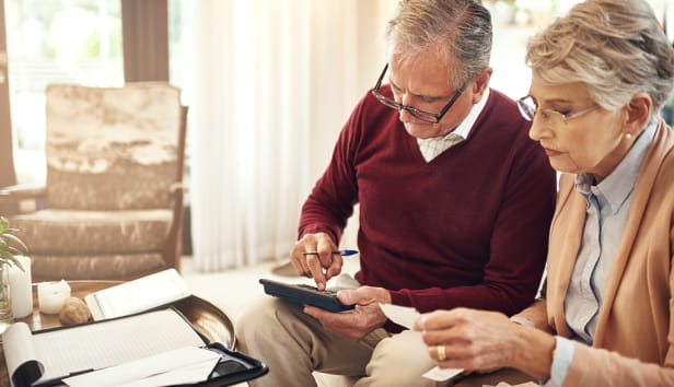 A man and woman sat with paperwork and a calculator