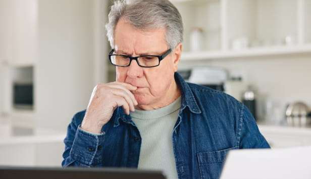 A man pensively looking at his laptop screen