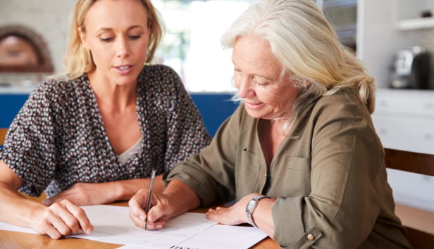 Two women sat at a desk signing papers