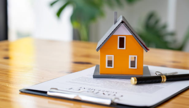 A miniature house sat on paper on a desk