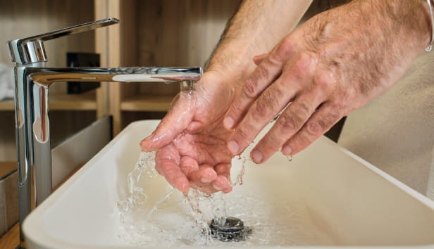 A man washing his hands under a tap
