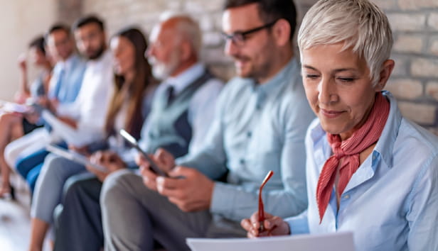 Line of people different ages sitting by wall while waiting their turn for job interview.
