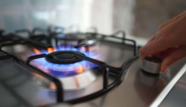 Woman turning on the gas burner on the stove.
