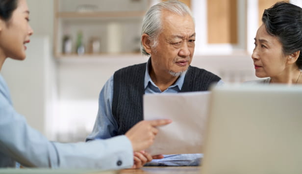 Senior asian couple appears confused by and suspicious at a sales person selling financial product.