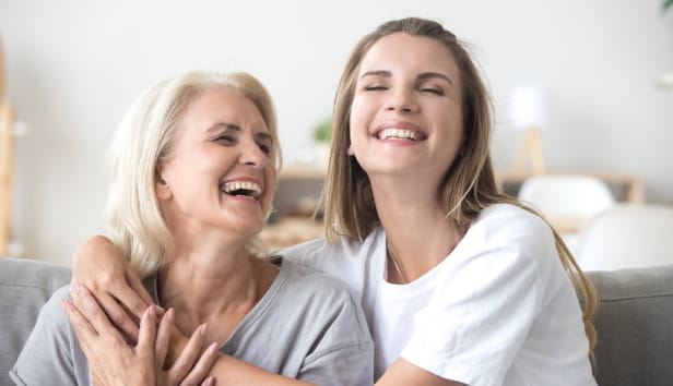 Happy senior mature mother embracing young adult woman laughing together, smiling elderly older mum joking having fun with grown daughter, two age generations humour and positive emotions concept.