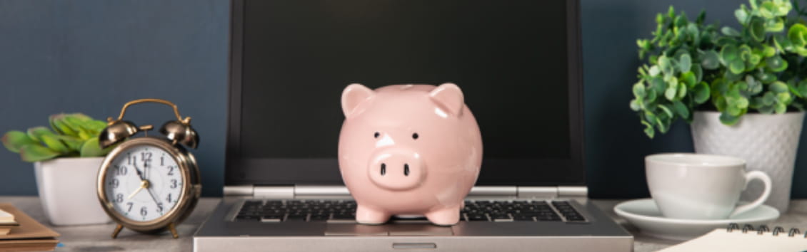 Piggy bank on the notebook with clock on working table