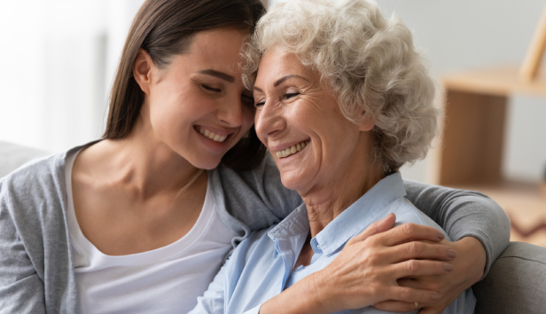 Positive smiling old grandma mother and young adult granddaughter daughter bonding at home, happy two generation women family laughing hugging having fun enjoying time together at reunion meeting.