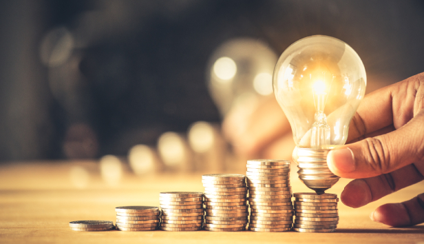 Hand holding a light bulb with coins stack. Creative ideas for saving money concept. Money management for the future.