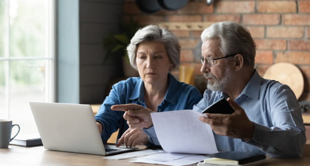 Mature couple sitting on a table looking at a contract 