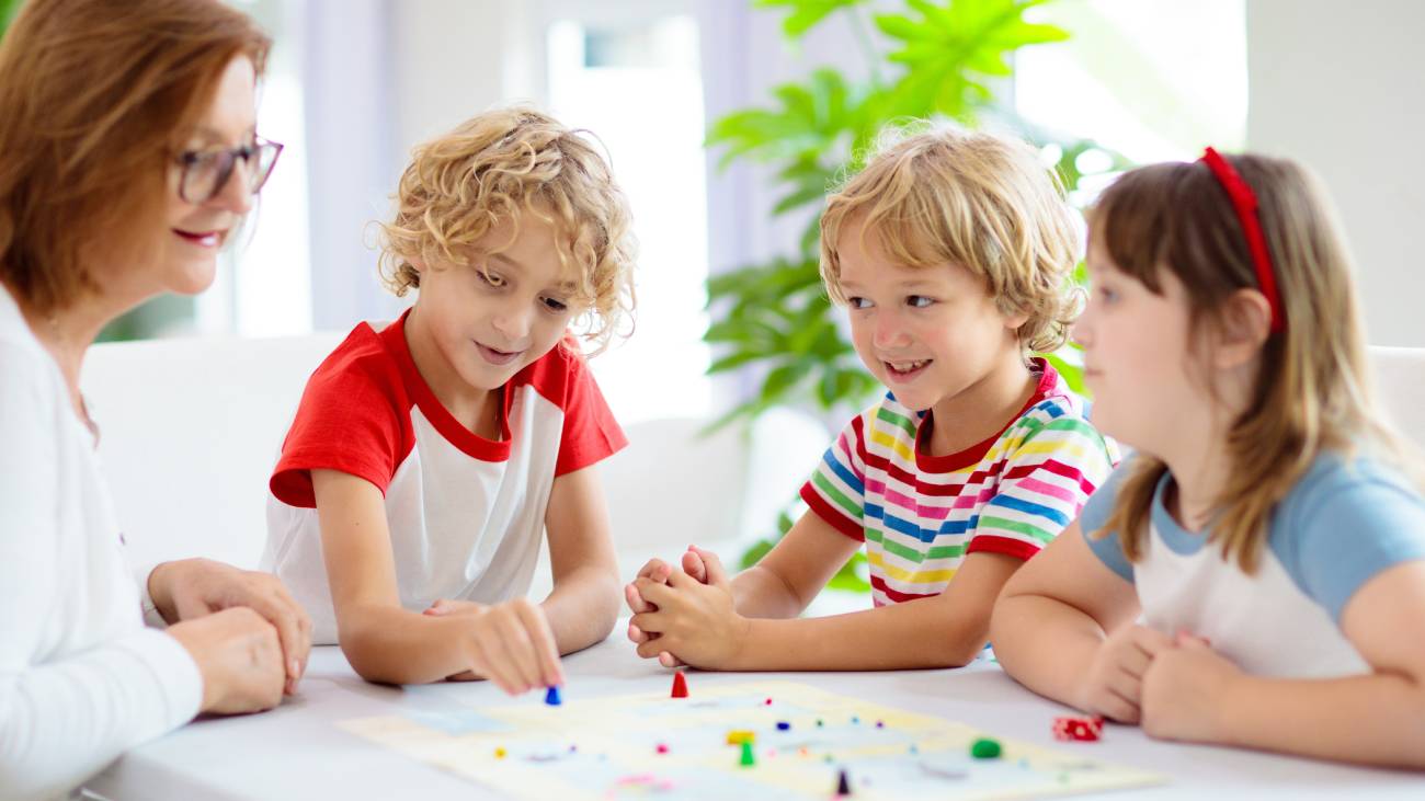 Children around a table playing board game with their parent smiling and having fun