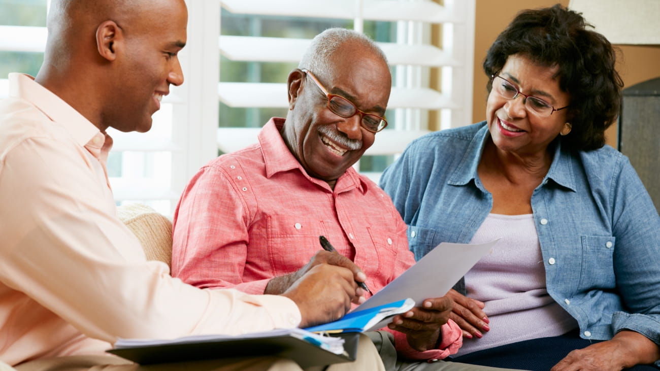 A couple sat next to a man signing a document